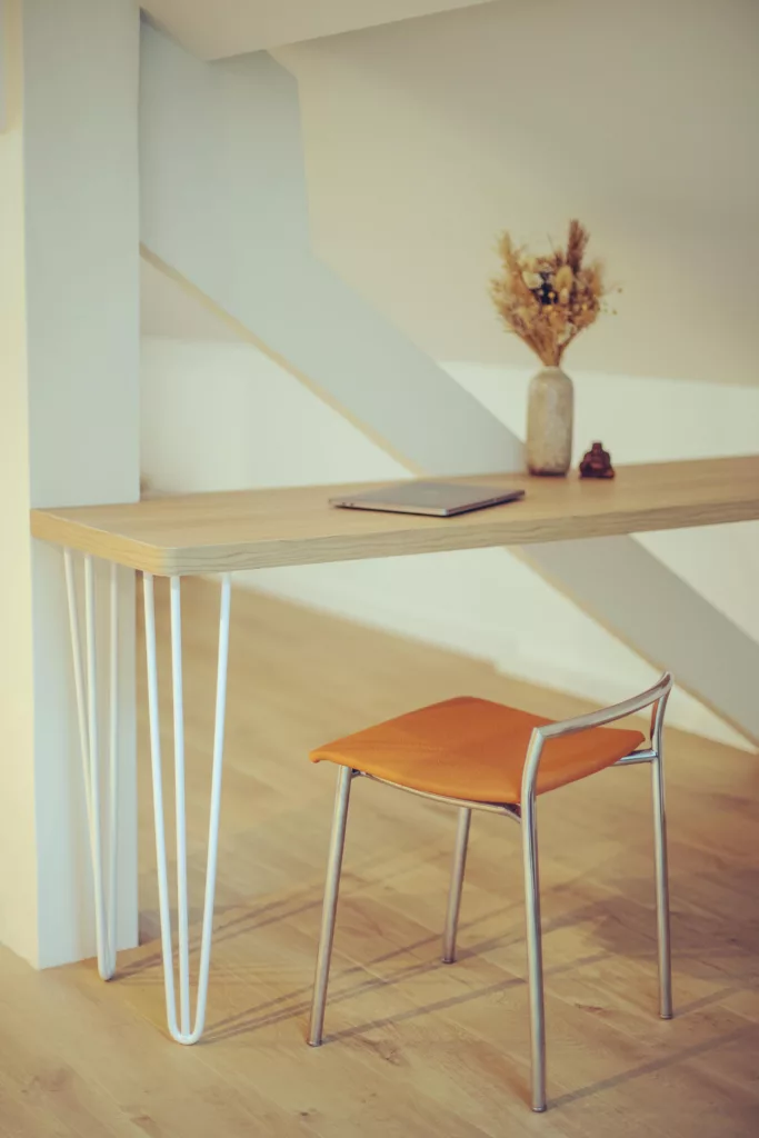 Espace bureau organisé sous combles, laissant apparaitre un élément de charpente autrefois masqué dans une cloison.